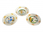 FAIANÇA SÃO CAETANO, três (3) pratos decorativos confeccionados em faiança na tonalidade branca, bordas com filetes verdes e decoração policromada, apresentando faixa ornamental com cogumelos e cenas centrais figurativas em estilo europeu, sendo uma cena de interior, uma cena de cozinha/padeiro e uma cena campestre com caçador, 1 bicado na borda, medindo 18cm de diâmetro.