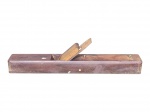 FERRAMENTA, uma (1) plaina confeccionada em madeira escura, acompanha lâmina com sinais de oxidação e ausência da alça e pega, medindo 12x46,5x6cm.