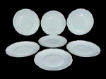 PORCELANAS, sete (7) pratos rasos confeccionados em porcelana na tonalidade branca, moldada na pasta por elementos florais e geométricos em relevo com recortes na borda, medindo 25cm de diâmetro.