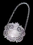 PRATA DE LEI, um (1) gravata para garrafa confeccionada em PRATA DE LEI, contrastada 833, cinzelada por elementos vegetalistas e capacete medieval em recortes, medindo 14x6,5cm e  peso 23,7g.