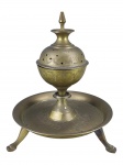 BRONZE INDIANO, um (1) incensário confeccionado em bronze, corpo bojudo cinzelado por folhagens, apoiada sobre presentoir, apoiado sobre 3 pés curvos, pega da tampa torneada, medindo 19x16,5cm.