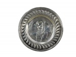 METAL PRATEADO, um (1) prato decorativo representando Hans Sachs, cercado por inscrição em relevo e borda ornamentada com gomos torcidos e folhagens, apresenta mossa e rachadura ao centro, medindo 24,5cm de diâmetro. Banho novo.