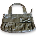 BOLSA DE MÃO CONFECCIONADA EM COURO, COR VERDE-OLIVA, COM DETALHES FRANZIDOS NA PARTE FRONTAL, DUAS ALÇAS FIXAS, ACABAMENTO EM COSTURAS APARENTES CONTRASTANTES E DETALHE DECORATIVO EM FORMATO DE LAÇO APLICADO NA PARTE FRONTAL, FECHAMENTO SUPERIOR EM ZÍPER, INTERIOR REVESTIDO EM TECIDO, CONTANDO COM COMPARTIMENTO INTERNO COM FECHAMENTO EM ZÍPER E OUTRO BOLSO ORGANIZADOR. TRATA-SE DE PEÇA SEMINOVA, PODENDO APRESENTAR SINAIS DE USO, MARCAS DO TEMPO, DESGASTES NATURAIS, PEQUENAS IMPERFEIÇÕES, RESTAUROS, REPAROS E/OU OUTRAS CARACTERÍSTICAS PRÓPRIAS DE SUA NATUREZA, USO E ESTADO DE CONSERVAÇÃO, NÃO SENDO TAIS ASPECTOS, POR SI SÓ, MOTIVO PARA DESCLASSIFICAÇÃO, CANCELAMENTO OU QUESTIONAMENTOS POSTERIORES, DEVENDO O ARREMATANTE CONSIDERAR TAIS CONDIÇÕES PREVIAMENTE À OFERTA E ARREMATAÇÃO.