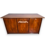 BUFFET EXECUTADO EM MADEIRA BRILHOSA, TRÊS PORTAS FRONTAIS E APLICAÇÃO ENTALHADA COM MOTIVOS FLORAIS NA PORTA CENTRAL, MEDINDO 80 X 145 X 50 CM. APRESENTA MARCAS DO TEMPO, USO, DESGASTES, RISCOS E/OU PEQUENAS IMPERFEIÇÕES COMPATÍVEIS COM SUA UTILIZAÇÃO E ESTADO DE CONSERVAÇÃO, CONFORME FOTOS EXTRAS. INFORMAMOS AINDA QUE NÃO REALIZAMOS EMBALAGEM DE MÓVEIS, SENDO A RETIRADA, ACONDICIONAMENTO, PROTEÇÃO E TRANSPORTE DE TOTAL RESPONSABILIDADE DO ARREMATANTE E/OU TRANSPORTADOR CONTRATADO.