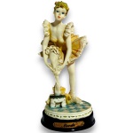 MONDE - ESCULTURA EXECUTADA EM RESINA, REPRESENTANDO BAILARINA EM POSIÇÃO DE AJUSTE DAS SAPATILHAS, COM RICA MODELAGEM DAS VESTES, EXPRESSÃO FACIAL E ELEMENTOS ORNAMENTAIS, APOIADA SOBRE BASE CIRCULAR EM MADEIRA COM PLAQUETA FRONTAL IDENTIFICADA, MEDINDO 19 X 9 CM. APRESENTA MARCAS DO TEMPO, USO, DESGASTES NA PATINAÇÃO E/OU PEQUENAS IMPERFEIÇÕES COMPATÍVEIS COM SUA UTILIZAÇÃO E ESTADO DE CONSERVAÇÃO, CONFORME FOTOS EXTRAS.