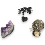 CONJUNTO DECORATIVO, INSPIRAÇÃO MÍSTICA E NATURALISTA, EXECUTADO EM MATERIAIS, TÉCNICAS, MARCAS, MODELOS, MEDIDAS, FORMATOS, TAMANHOS, UTILIDADES E PROCEDÊNCIAS DIVERSOS COMPOSTO POR TRÊS PEÇAS, SENDO: UMA DRUSA, DITO GEODO, EM AMETISTA COM FORMAÇÃO CRISTALINA NATURAL, MEDINDO 6 X 7 X 3 CM; ÁRVORE DA FELICIDADE, ESTRUTURA ARAMADA EM METAL E PEDRA NATURAL SOBRE BASE EM RESINA, MEDINDO 7 CM E ÁRVORE DA PROSPERIDADE EM PEDRARIAS NATURAIS FIXADA SOBRE BASE EM MADEIRA, MARCA MARIA DE MINHAS, MODELO ÁGATA LILÁS, MEDINDO 7 CM. APRESENTAM MARCAS DO TEMPO, USO, DESGASTES NA PATINAÇÃO, PEQUENAS PERDAS E/OU IMPERFEIÇÕES COMPATÍVEIS COM SUA UTILIZAÇÃO E ESTADO DE CONSERVAÇÃO, CONFORME FOTOS EXTRAS.