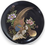 ARTE ORIENTAL - PRATO DECORATIVO EXECUTADO EM CERÂMICA ESMALTADA E VITRIFICADA, ORNADO COM CENA DE INSPIRAÇÃO ORIENTAL REPRESENTANDO AVES SOBRE ROCHEDOS ENTRE FLORES E FOLHAGENS, COM RICO TRABALHO EM DOURAÇÃO E DECORAÇÃO POLICROMADA SOBRE FUNDO ESCURO, COM ACABAMENTO BRILHANTE, DETALHAMENTO MINUCIOSO, ASSINATURA EM SELO PRETO COM BORDA DUPLA VERMELHA, MEDINDO 15 CM. APRESENTA MARCAS DO TEMPO, USO, PEQUENOS RISCOS, DESGASTES NA DOURAÇÃO E/OU IMPERFEIÇÕES COMPATÍVEIS COM SUA UTILIZAÇÃO E ESTADO DE CONSERVAÇÃO, CONFORME FOTOS EXTRAS.