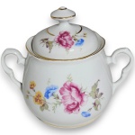 SCHMIDT - AÇUCAREIRO, EXECUTADO EM PORCELANA ESMALTADA E VITRIFICADA, APRESENTANDO CORPO DE FORMATO BOJUDO DECORADO COM RAMOS E FLORES EM ARRANJO FLORAL NA TÉCNICA DITA DECALQUE, DOTADO DE DUAS ALÇAS LATERAIS SIMÉTRICAS ORNAMENTADOS COM VOLUTAS E RELEVOS, TAMPA REMOVÍVEL ENCIMADA COM PEGA HEXAGONAL CENTRALIZADA E BASE ANELAR DE PERFIL LISO, APRESENTANDO FILETES EM DOURADO APLICADOS NAS BORDAS, NAS ALÇAS E NA PEGA, MEDINDO 12 X 14 X 8,5 CM APRESENTANDO MARCAS DO TEMPO, USO, PEQUENOS RISCOS, DISCRETOS DESGASTES NO DOURADO PERIFÉRICO E/OU IMPERFEIÇÕES COMPATÍVEIS COM SUA UTILIZAÇÃO E ESTADO DE CONSERVAÇÃO, CONFORME FOTOS EXTRAS.