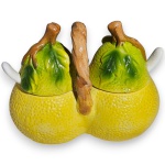 GALHETEIRO DUPLO EXECUTADO EM CERÂMICA ESMALTADA E VITRIFICADA, MOLDADO ARTISTICAMENTE NO FORMATO DE FRUTAS CÍTRICAS UNIDAS PELA BASE, COM CORPO TEXTURIZADO SIMULANDO CASCA DE FRUTA, TAMPAS REMOVÍVEIS ORNADAS COM FOLHAGENS EM RELEVO E PUXADORES EM FORMATO DE CAULES, ALÇA CENTRAL MODELADA COMO GALHO RETORCIDO E ACOMPANHADO DE DUAS PEQUENAS COLHERES EM CERÂMICA ACONDICIONADAS EM ABERTURAS LATERAIS, IDEAL PARA SERVIR CONDIMENTOS, MOLHOS OU ESPECIARIAS, COM ACABAMENTO BRILHANTE E DETALHAMENTO MINUCIOSO, MEDINDO APROXIMADAMENTE 16 X 15 X 8 CM. APRESENTA MARCAS DO TEMPO, USO, PEQUENOS RISCOS, DESGASTES, PEQUENAS AVARIAS E/OU IMPERFEIÇÕES COMPATÍVEIS COM SUA UTILIZAÇÃO E ESTADO DE CONSERVAÇÃO, CONFORME FOTOS EXTRAS.