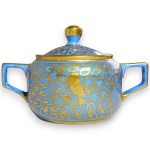 TK THUN - AÇUCAREIRO, MADE IN CZECHOSLOVAKIA, EXECUTADO EM PORCELANA ESMALTADA E VITRIFICADA, CORPO CILÍNDRICO COM ALÇAS ESTILIZADAS DE LINHAS RETAS, RICAMENTE ORNADO COM DENSA DECORAÇÃO APRESENTANDO ELEMENTOS FITOMÓRFICOS, VOLUTAS E PÁSSAROS EM INTENSO DOURADO, ACOMPANHADO DE RESPECTIVA TAMPA ENCIMADA COM PEGA, MEDINDO 9 X 13 X 8,5 CM. APRESENTA MARCAS DO TEMPO, USO, PEQUENOS RISCOS, DESGASTES NA DOURAÇÃO, MANCHAS, PEQUENAS AVARIAS E/OU IMPERFEIÇÕES COMPATÍVEIS COM SUA UTILIZAÇÃO E ESTADO DE CONSERVAÇÃO, CONFORME FOTOS EXTRAS.9 X 13 X 8,5 CM