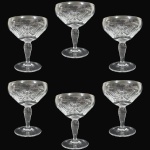 CONJUNTO DE TAÇAS PARA CHAMPANHE E/OU SOBREMESAS EXECUTADO EM DEMI-CRISTAL, APRESENTANDO CORPO EM FORMATO DE CÁLICE COPA LARGA REBAIXADA RICAMENTE ORNADO COM LAPIDAÇÃO EM ESTRELA MULTIFACETADA, SULCOS E FRISOS RADIAIS, ASSENTADO SOBRE HASTE BALAUSTRADA SOBRE BASE CIRCULAR, COMPOSTO POR SEIS PEÇAS, MEDINDO 11 X 9 CM CADA. APRESENTAM MARCAS DO TEMPO, USO, PEQUENOS RISCOS, MANCHAS, PEQUENOS DESGASTES E/OU IMPERFEIÇÕES COMPATÍVEIS COM SUA UTILIZAÇÃO E ESTADO DE CONSERVAÇÃO, CONFORME FOTOS EXTRAS.