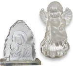 CONJUNTO DE ESCULTURAS EXECUTADAS EM VIDRO ARTÍSTICO, TRABALHADO ARTESANALMENTE, SENDO: UMA, REPRESENTANDO ANJO SENTADO, COM ACABAMENTO SATINADO, MEDINDO 11,5 X 6,5 CM E UMA, EM FORMATO DE GRUTA COM EFÍGIE DE NOSSA SENHORA COM MENINO JESUS EM BAIXO-RELEVO JATEADO NO VERSO, MEDINDO 10 X 8,5 CM. APRESENTAM MARCAS DO TEMPO, USO, PEQUENOS RISCOS, MANCHAS, PEQUENOS DESGASTES E/OU IMPERFEIÇÕES COMPATÍVEIS COM SUA UTILIZAÇÃO E ESTADO DE CONSERVAÇÃO, CONFORME FOTOS EXTRAS. ESCLAREÇA TODAS AS DÚVIDAS ANTES DE EFETUAR SEU LANCE, QUE SERÁ CONSIDERADO IRREVOGÁVEL E IRRETRATÁVEL. CONSULTE PREVIAMENTE OS TERMOS E CONDIÇÕES DISPONÍVEIS NO SITE. CONTATO (21) 98264-3000.