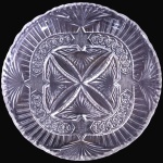 PRATO PARA SOBREMESAS E/OU SALADAS EXECUTADO EM VIDRO TRANSLÚCIDO MOLDADO E LAPIDADO, COM CORPO DE FORMATO CIRCULAR INTEGRALMENTE DECORADO EM MOTIVOS GEOMÉTRICOS EM RELEVO, APRESENTANDO MEDALHÃO CENTRAL EM FORMATO DE MANDALA COM QUATRO GRANDES PÉTALAS EM PALMETES, CIRCUNDADO POR FRISO RENDILHADO COM PEQUENAS ROSÁCEAS ESTRELADAS, ALÉM DE BORDA EXPANSÍVEL REPLETA DE ELEMENTOS CANELADOS E SULCOS RADIANTES COM BORDA SUPERIOR RECORTADA E ONDULADA, MEDINDO 2,5 X 25 CM. APRESENTA MARCAS DO TEMPO, USO, DESGASTES E/OU IMPERFEIÇÕES COMPATÍVEIS COM SUA UTILIZAÇÃO E ESTADO DE CONSERVAÇÃO, CONFORME FOTOS EXTRAS. ESCLAREÇA TODAS AS DÚVIDAS ANTES DE EFETUAR SEU LANCE, QUE SERÁ CONSIDERADO IRREVOGÁVEL E IRRETRATÁVEL. CONSULTE PREVIAMENTE OS TERMOS E CONDIÇÕES DISPONÍVEIS NO SITE. CONTATO (21) 98264-3000.