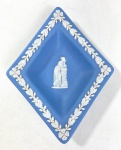 WEDGWOOD ENGLAND - PRATINHO LOSANGULAR EM JASPER AZUL E BRANCO COM MOTIVOS EM ESTILO NEOCLÁSSICO, MANUFATURA NO VERSO EM BAIXO RELEVO . MEDIDAS: 14 x 11 CM. CURIOSIDADES: EM 1738 COMEÇARAM AS ESCAVAÇÕES DE POMPEIA E HERCULANO PRÓXIMO DE NÁPOLES NA ITÁLIA CRIANDO A PARTIR DESSA ÉPOCA, NA EUROPA, UM NOVO INTERESSE AO ESTILO NEOCLÁSSICO. EM 1759, JOSIAH WEDGWOOD FUNDOU UMA MANUFATORA DE PORCELANA INSPIRADA EM MOTIVOS DA ANTIGUIDADE CLÁSSICA, TORNANDO SUA EMPRESA CONSAGRADA MUNDIALMENTE. AS PEÇAS ERAM REALIZADAS COM UM TIPO DE MATERIAL AO QUAL FOI DADO O NOME DE JASPER