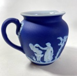 WEDGWOOD ENGLAND - CREMEIRA EM JASPER MARINHO E  BRANCO COM MOTIVOS EM ESTILO NEOCLÁSSICO, MEDIDAS: 8,5 X 7 CM. CURIOSIDADES: EM 1738 COMEÇARAM AS ESCAVAÇÕES DE POMPEIA E HERCULANO PRÓXIMO DE NÁPOLES NA ITÁLIA CRIANDO A PARTIR DESSA ÉPOCA, NA EUROPA, UM NOVO INTERESSE AO ESTILO NEOCLÁSSICO. EM 1759, JOSIAH WEDGWOOD FUNDOU UMA MANUFATORA DE PORCELANA INSPIRADA EM MOTIVOS DA ANTIGUIDADE CLÁSSICA, TORNANDO SUA EMPRESA CONSAGRADA MUNDIALMENTE. AS PEÇAS ERAM REALIZADAS COM UM TIPO DE MATERIAL AO QUAL FOI DADO O NOME DE JASPER