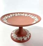 WEDGWOOD ENGLAND - PRATO PÉ ALTO EM JASPER ROSA E BRANCO COM MOTIVOS EM ESTILO NEOCLÁSSICO, MANUFATURA NO VERSO EM BAIXO RELEVO . MEDIDAS:9 X 15  CM. CURIOSIDADES: EM 1738 COMEÇARAM AS ESCAVAÇÕES DE POMPEIA E HERCULANO PRÓXIMO DE NÁPOLES NA ITÁLIA CRIANDO A PARTIR DESSA ÉPOCA, NA EUROPA, UM NOVO INTERESSE AO ESTILO NEOCLÁSSICO. EM 1759, JOSIAH WEDGWOOD FUNDOU UMA MANUFATORA DE PORCELANA INSPIRADA EM MOTIVOS DA ANTIGUIDADE CLÁSSICA, TORNANDO SUA EMPRESA CONSAGRADA MUNDIALMENTE. AS PEÇAS ERAM REALIZADAS COM UM TIPO DE MATERIAL AO QUAL FOI DADO O NOME DE JASPER