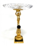 ANTIGO CENTRO DE MESA, BASE EM BRONZE DOURADO COM DETALHES DE PÁTINA, HASTE NA FIGURA DE MENINO SUSTENTANDO PRATO EM CRISTAL TRANSLÚCIDO. MEDIDAS: 42 X 32 CM