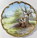 MEDALHÃO  EM PORCELANA EUROPEIA PROVAVELMENTE ALEMÂ DA REGIÃO DA BAVIERA/DRESDEN CIRCA 1825-1920 - CORPO RECORTADO EM FORMATO ROCAILLE COM RICA DOURAÇÃO A OURO FINO EM ALTO BRUNIDO. CENTRO DECORADO COM CENA CAMPESTRE ROMÂNTICA REPRESENTANDO JOVENS ALDEÃS JUNTO Á ARVORE E FEIXE DE COLHEITA, EXECUTADA EM PINTURA MANUAL POLICROMADA. NO VERSO A MARCA DA MANUFATURA. MEDIDAS: 29 CM