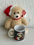 OBJETOS DECORATIVOS - Lote com 2 itens natalinos - [Item 1] Caneca de cerâmica branca com estampa de Papai Noel; [Item 2] Pelúcia de urso natalino com gorro e cachecol vermelho, medindo aproximadamente 20x15x21cm, com etiqueta. Peças em bom estado geral.