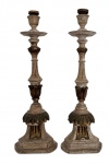 MINAS SÉC. XIX - Par de tocheiros sacros em madeira entalhada, ricamente ornamentados com motivos vegetalistas e elementos em douração ao estilo barroco mineiro, apresentando pátina envelhecida em tons claros. Bases quadrangulares escalonadas e hastes torneadas com detalhes clássicos, conferindo elegância e presença decorativa. Pontas metálicas. Mede 45 cm altura.