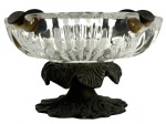 Cinzeiro antigo em vidro prensado translúcido, corpo com decoração em relevo radial e quatro apoios para cigarro em metal patinado. Base elevada com suporte em metal fundido de desenho orgânico, conferindo elegância ao conjunto. Peça de caráter utilitário com apelo decorativo, apresentando marcas do tempo compatíveis com a idade. Mede 11cm de diâmetro.