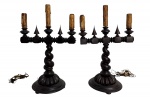 Par de candelabros antigos de estilo Manuelino, em madeira torneada e patinada em tom escuro, com hastes em espiral e elementos decorativos entalhados. Corpo com suportes para velas elétricas simulando castiçais antigos. Apresentam sinais do tempo e uso. Possui fiação, funcionamento desconhecido. Mede 55 x 35 cm.