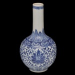 Moringa em porcelana chinesa com decoração em tons de azul, apresentando corpo bojudo e gargalo longo. A peça possui pintura vegetalista, incluindo motivos florais e folhagens, além de ser descrita como apresentando um selo azul na base. Marca da manufatura no verso. 20 x 11 cm.