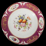 PRATO D. PEDRO I - Prato do serviço Barra Bordeaux de porcelana possivelmente francesa. Século XIX. Sem marca. Apresenta barrado bordô com dourado e três reserva com flores, na caldeira ramo florido. Reproduzido a página 190 do livro Louça da Aristocracia No Brasil. 23 cm.