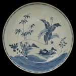 CHINA. Séc. XX - Prato em porcelana chinesa. Formato circular apresentando motivos clássicos de paisagem ou elementos naturais tais como bambu e folhagens em tons de azul sobre fundo branco.  Marca da manufatura na base.5 x 26 cm.