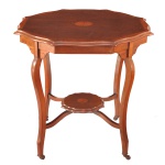 Mesa lateral octogonal do estilo inglês do período Eduardiano Feita de madeira nobre (mogno) com marchetaria decorativa no tampo superior e na prateleira inferior. Apresenta um tampo superior recortado em formato octogonal, acompanhado por uma segunda prateleira inferior menor que repete o mesmo padrão geométrico. O centro de ambos os níveis exibe um medalhão circular em marchetaria em tons contrastantes de madeira mais clara), característico do requinte mobiliário da virada do século XIX para o século XX.  Pernas longas e elegantemente arqueadas no estilo cabriole, que se unem na parte inferior para dar suporte à prateleira secundária, finalizadas com pés discretos em formato de voluta. 72 x 77  x 77 cm.