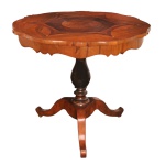 Séc. XIX - Mesa lateral em madeira nobre  marchetada. Apresenta um estilo clássico europeu  muito associado à produção inglesa do período vitoriano. Possui formato circular com bordas recortadas e sinuosas (estilo gueridon). O centro exibe um trabalho refinado de marchetaria geométrica e folheados de tonalidades contrastantes. A sustentação é feita por um coluna central torneado com acabamento escurecido, criando um elegante contraste visual com o tampo apoiado sobre três pernas recurvadas e onduladas, que garantem estabilidade sem ocupar muito espaço no piso. 80 x 92 cm.