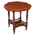 Séc. XIX - Mesa lateral inglesa, período vitoriano. Possui um tampo octogonal moldado em madeira nobre (mogno).  Conta com quatro pernas principais ricamente torneadas em anéis  O grande charme desta mesa está na prateleira inferior, que serve como uma travessa de suporte estrutural, cercada por uma delicada e detalhada galeria de balaústres torneados.  Base termina em pés com rodízios de metal típicos da época, projetados para facilitar o deslocamento do mesa. 70 x 60 x 60 cm.