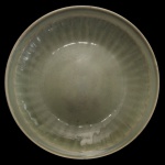 Medalhão circular em porcelana chinesa, revestido por coberta celadon de cor verde. Apresenta decoração com gomos, centralizando fundo liso. Peça em estilo da dinastia Ming. 6 x 33 cm.