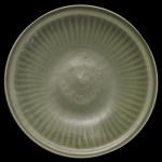 Medalhão circular em porcelana chinesa, revestido por coberta celadon de cor verde. Apresenta decoração com gomos, centralizando estilização em leve relevo. Peça em estilo da dinastia Ming. 10 x 45 cm.