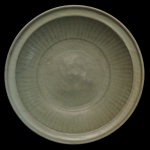 Medalhão circular em porcelana chinesa, revestido por coberta celadon de cor verde. Apresenta decoração com gomos, centralizando estilização em leve relevo. Verso com manchas. Peça em estilo da dinastia Ming. 8 x 32 cm.
