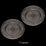 Conjunto de sousplat em vidro translucido com acabamento em relevo ornamental. Esse design clássico, muitas vezes chamado de estilo barroco, apresenta detalhes florais e volutas esculpidas em toda a borda e ao redor do centro. 30 cm.