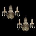 Par de arandelas antigas de estilo Império, confeccionadas com estrutura em bronze e ornamentadas com pingentes facetados e contas de cristal. Esse design clássico, também conhecido comercialmente como formato "cesta" ou "balão", traz braços laterais integrados que imitam o formato de velas decorativas.