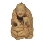 Japão. Netsuke, em marfim policromado, representando uma figura humana detalhada operando ou segurando uma grande sacola ou fole, um tema clássico que ilustra profissões, divindades ou contos folclóricos do cotidiano japonês. São pequenas figuras detalhadas feitas no formato tradicional de netsuke (peças decorativas usadas originalmente como fechos de bolsas no Japão tradicional) ou okimono (estatuetas para exibição). Tradicionalmente entalhadas em marfim ou madeira de buxo (boxwood), com detalhes realçados em nanquim escuro para dar profundidade às feições e vestimentas.