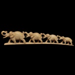Escultura oriental clássica de "ponte de elefantes" esculpida em marfim, muito popular no artesanato tradicional Tradicionalmente feita a partir de uma presa inteira de marfim de elefante, acompanhando a curvatura natural do dente. Apresenta uma manada ou família de elefantes esculpidos em tamanhos decrescentes ou graduados, caminhando em fila única. Na cultura oriental, a figura do elefante atrai boa sorte, prosperidade, sabedoria e proteção para o lar, sendo a manada unida um forte símbolo de fidelidade e força familiar.