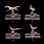 Conjunto de porta-cartões de mesa vintage (place card holders), comumente utilizados para indicar os assentos de convidados em jantares formais. As peças são miniaturas esculpidas em metal prateado. Apresentam uma temática decorativa voltada à fauna campestre e aves de caça (como faisões e patos), detalhadamente montadas sobre pequenas bases de formato cilíndrico ou de troncos. Cada suporte possui uma pequena fenda horizontal em sua base de acrílico projetada especificamente para fixar e exibir os cartões com os nomes dos convidados.