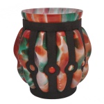 CHARLES SCHNEIDER - Belíssimo vaso em vidro soprado no estilo Art Déco francês (estilo pâte de verre), produzido por volta da década de 1920 ou 1930. Esse design icônico é frequentemente associado a colaborações históricas de mestres vidreiros com ferreiros artísticos da época, como as famosas parcerias entre as  criações dos estúdios de Charles Schneider. O vidro incandescente multicolorido mesclando tons de verde, laranja, vermelho e branco é assoprado diretamente por dentro de uma estrutura oca de ferro batido. À medida que o vidro expande, ele se projeta para fora através das aberturas da gaiola metálica, criando gomos abaulados tridimensionais característicos da estética moderna do início do Século XX.