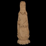 Estatueta chinesa em marfim representando Kwan Yin, a deusa da Compaixão, de pé sobre base formada por pétalas de lotus. Exibe tradicional tiara sobre a cabeça, e segura nas mãos um rosário e o Sutra, rolo com escritura sagrada, símbolo da Sabedoria Divina. 13 x 14 cm.