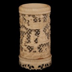 Elegante Bitong, pote chinês para pinceis de formato cilíndrico, finamente esculpido em marfim. Apresenta cena palaciana com figuras sobre fundo vazado por estrelas, encimado por friso dentado e borda em debrum. Base circular com faixa inferior ornamentada por arabescos e folhagens. Assinatura a nanquim sob a base.10 x 6 cm.