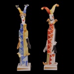 MEISSEN  Original par de figuras  em porcelana alemã, representando casal de carnavalescos com corpos estilizados. Exibem-se com vistosos trajes com estampas geométricas policromadas, de pé sobre bases quadrangulares. Marcas da manufatura e numeração sob as bases.12 x 2 x 2 cm.