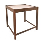SERGIO RODRIGUES - Mesa lateral estilo Mid-Century Modern (Modernista), produzida originalmente na década de 1950 ou 1960. Apresenta linhas retas minimalistas, com pernas de seção quadrada integradas à moldura superior e travessas de reforço na parte inferior. Estrutura é feita em madeira de lei maciça, acompanhada por um tampo revestido com laminado (fórmica) claro. 51 x 51 x 44 cm.