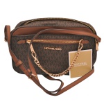 MICHAEL KORS - Bolsa Transversal modeo Jet Set Monograma. Confeccionada em canvas com o icônico padrão monograma de letras "MK" em tons de marrom. Possui detalhes e alças em couro caramelo/marrom, além de ferragens e logotipo frontal dourados. Conta com um bolso frontal de zíper decorado com uma corrente de metal polido, alça transversal ajustável e fechamento superior seguro por zíper.