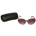 CHANEL. Óculos de sol modelo Chanel 5262 em degradê de rosa, caracterizado por uma armação translúcida em tom roxo/rosa degradê e hastes trabalhadas em filigrana prateada com brilhos. Formato oval oversized em acetato, com lentes escuras em degradê rosa/roxo. Detalhes intrincados de filigrana prateada metalizada com acabamento texturizado ou brilhante.