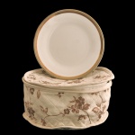 RICHARD GINORI, Italy - Conjunto composto de 12 pratos de porcelana italiana da manufatura Ginori. Apresenta uma base central em tom off-white com borda contrastante em degradê de dourado. Textura levemente salpicada e linhas concêntricas em relevo características do design rústico e atemporal da marca. 19 cm.