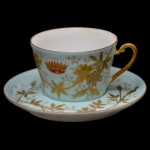 VISCONDE DE GUAY - Xícara com pires de porcelana francesa, pertencente ao Serviço do Visconde de Guay (Joaquim Elísio Pereira Marinho). Apresenta decoração em ambas as peças predominantemente em verde berilo, decorado com flores douradas em relevo. Na xícara ao centro, coroa de conde dourada em relevo. No fundo do pires a inscrição Deposé. Pasta dura. França. Séc. XIX. 6 x 10 cm / 14 cm pires.