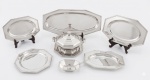 Aparelho de servir em aço Inox WOLFF com bordas oitavadas. Sem uso. Composto por: 1 sopeira, 1 presentoir,  5 travessas e uma molheira com colher. Total de 9 peças. Medida maior: 58 x 26 cm e menor: 13 x 17 x 04 cm